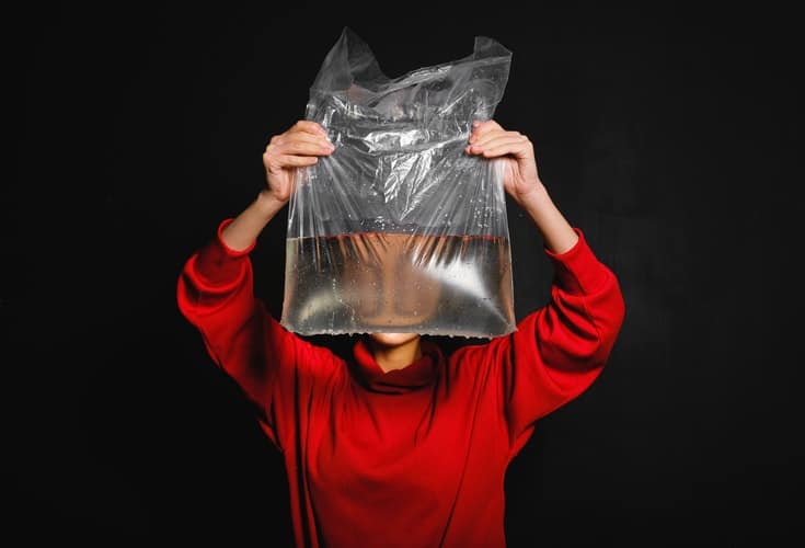 femme tenant un sac en plastique avec de l'eau